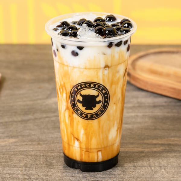 A close-up of a SnoCream Company bubble tea with brown sugar streaks and tapioca pearls.